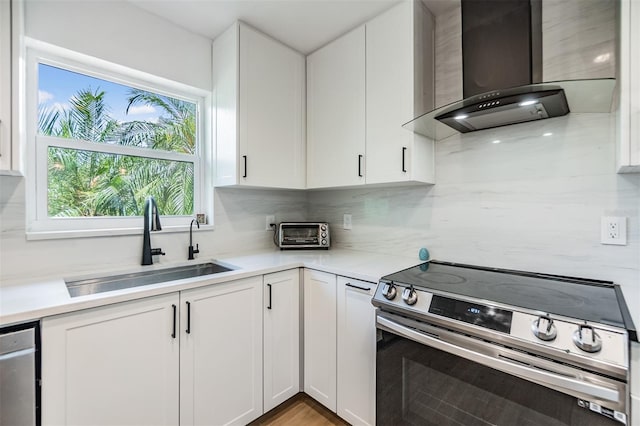 1400 Tarpon Woods Blvd Unit E4, Palm Harbor, FL 34685 - kitchen featuring appliances with stainless steel finishes, wall chimney range hood, a sink, and white cabinets
