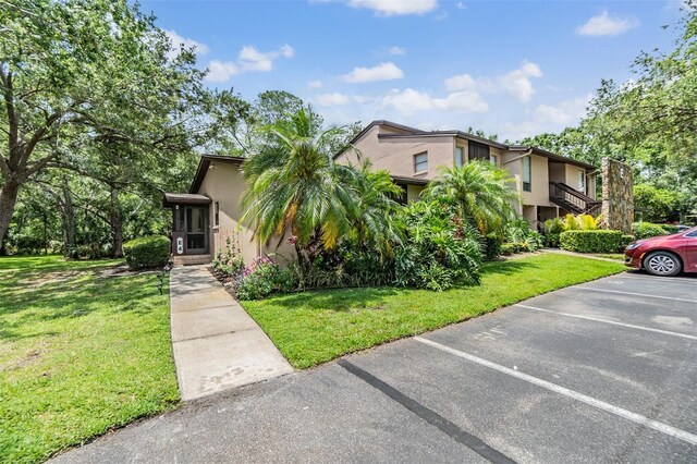 1400 Tarpon Woods Blvd Unit E4, Palm Harbor, FL 34685 - view of front of home featuring stucco siding, uncovered parking, and a front lawn