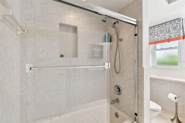 10387 Majestic Dr, Largo, FL 33774 - full bath featuring toilet, bath / shower combo with glass door, and tile walls