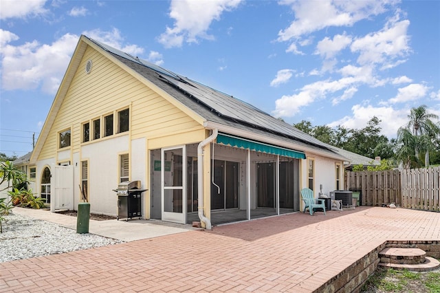7833 Ontario Street Cir, Sarasota, FL 34243 - back of property featuring a sunroom, a patio, solar panels, and stucco siding