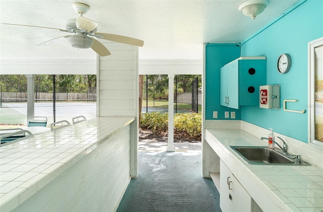 7833 Ontario Street Cir, Sarasota, FL 34243 - kitchen with tile counters, carpet floors, a ceiling fan, and white cabinets