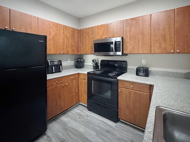 202 E S St Unit 5050, Orlando, FL 32801 - kitchen with black appliances, light wood finished floors, light countertops, and brown cabinets