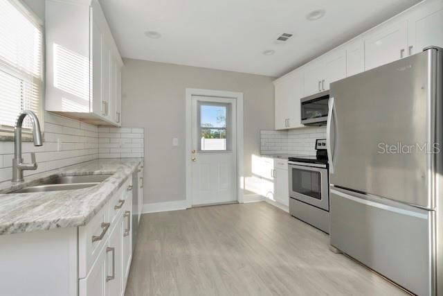 243 45th St N, Saint Petersburg, FL 33713 - kitchen with stainless steel appliances, a sink, tasteful backsplash, and white cabinetry
