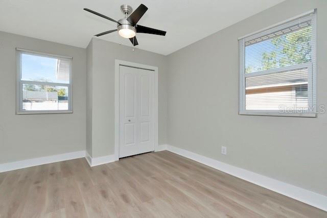 243 45th St N, Saint Petersburg, FL 33713 - unfurnished bedroom featuring baseboards, light wood-style floors, a closet, and a ceiling fan