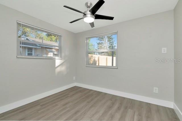 243 45th St N, Saint Petersburg, FL 33713 - unfurnished room featuring baseboards, wood finished floors, healthy amount of natural light, and ceiling fan