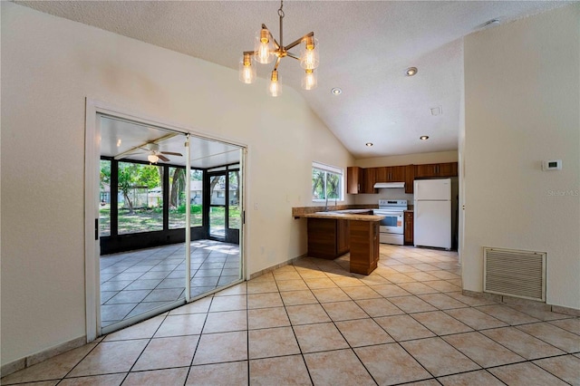 4032 Albany Rd, Labelle, FL 33935 - kitchen featuring white appliances, a peninsula, vaulted ceiling, light tile patterned flooring, and under cabinet range hood