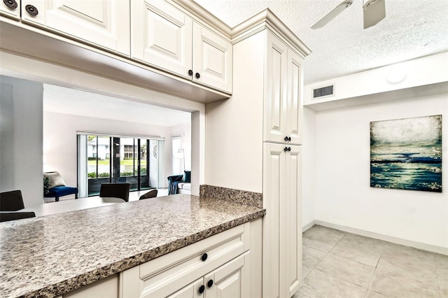 1109 Pine Ridge Cir W Unit C1, Tarpon Springs, FL 34688 - kitchen featuring light tile patterned floors, a ceiling fan, a textured ceiling, baseboards, and white cabinetry