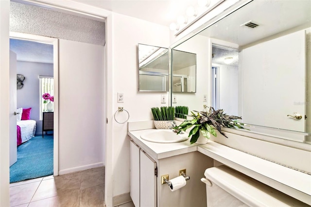 1109 Pine Ridge Cir W Unit C1, Tarpon Springs, FL 34688 - ensuite bathroom featuring vanity, tile patterned flooring, a textured ceiling, and baseboards