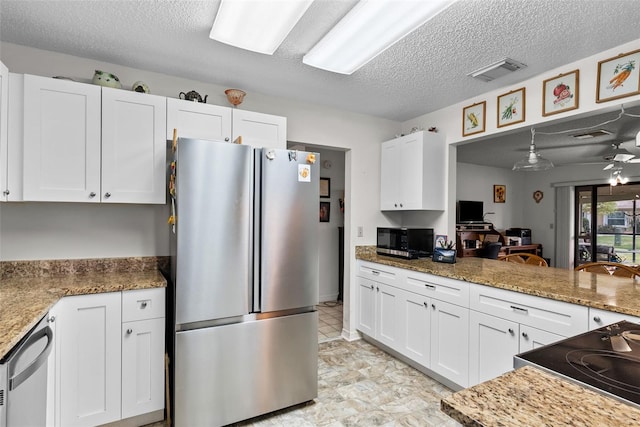 1633 Bentwood Dr, Sun City Center, FL 33573 - kitchen featuring stainless steel appliances, white cabinetry, a textured ceiling, and light stone countertops