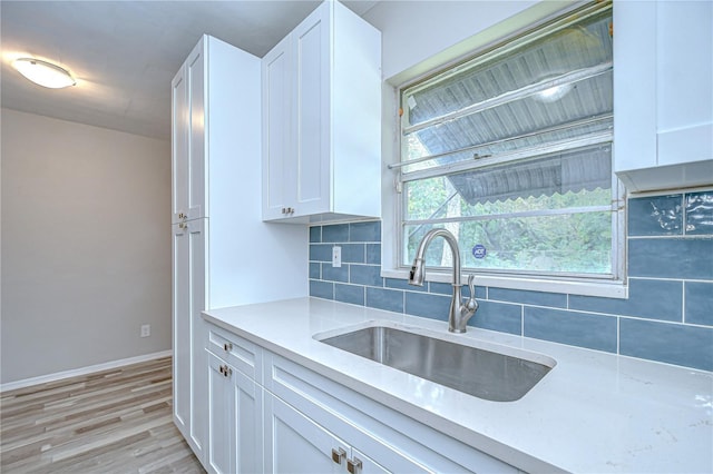 6004 S 82nd St, Tampa, FL 33619 - kitchen with a sink, decorative backsplash, white cabinets, light wood-style floors, and baseboards