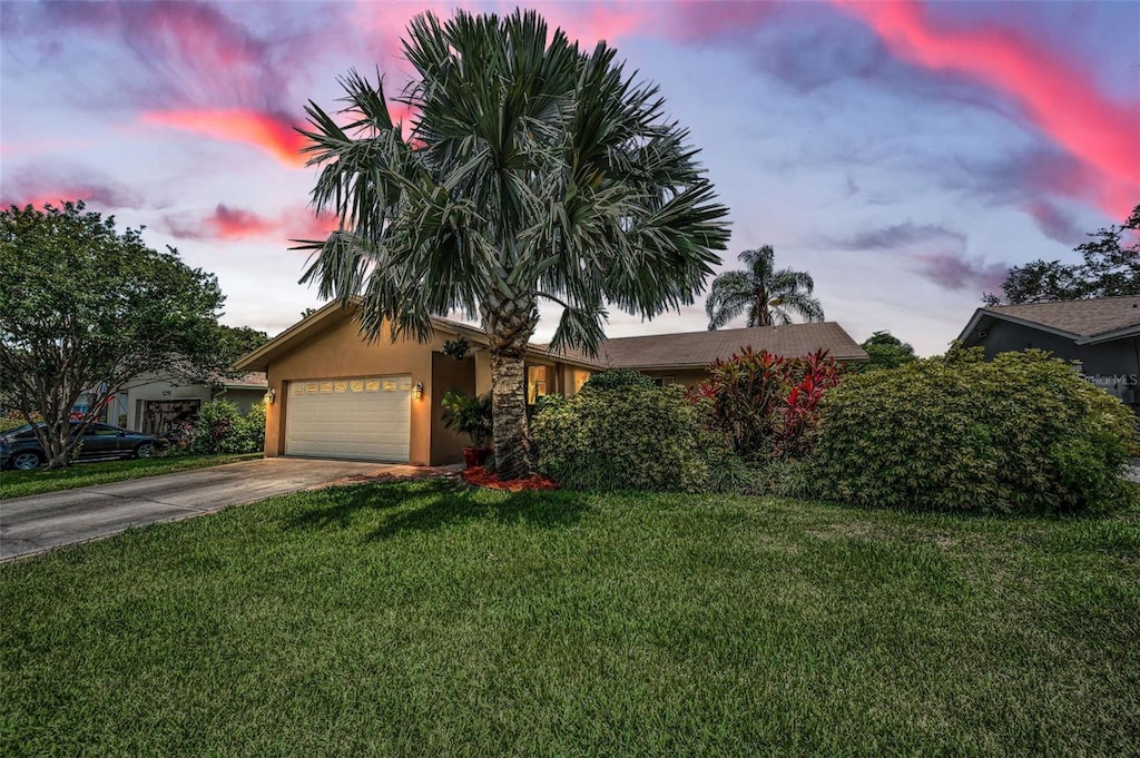 1281 Amberlea Dr E, Dunedin, FL 34698 - obstructed view of property featuring stucco siding, a garage, a front yard, and driveway