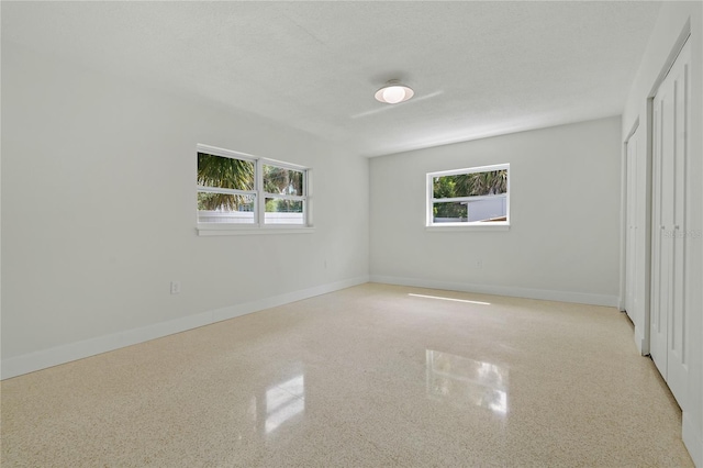 433 Pineapple St, Tarpon Springs, FL 34689 - unfurnished bedroom with multiple windows, baseboards, speckled floor, and a closet