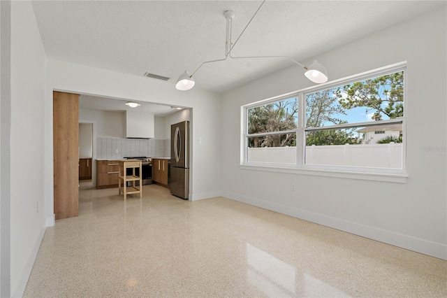 433 Pineapple St, Tarpon Springs, FL 34689 - unfurnished living room with baseboards, healthy amount of natural light, dark aggregate flooring, and a textured ceiling