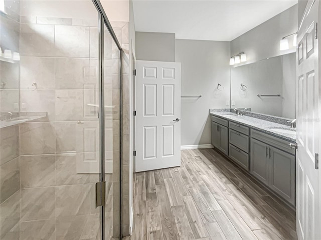 19664 Ship Wheel Way, Land O Lakes, FL 34638 - bathroom featuring a stall shower, double vanity, wood finished floors, and baseboards