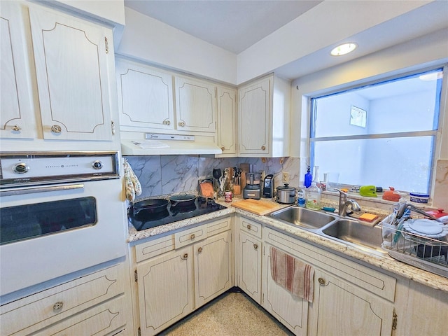 2066 High Ridge Dr, Clearwater, FL 33763 - kitchen with oven, black electric stovetop, under cabinet range hood, tasteful backsplash, and a sink