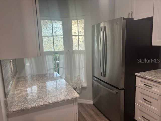 6520 Thicket Trl, New Port Richey, FL 34653 - kitchen featuring freestanding refrigerator, white cabinets, light stone countertops, baseboards, and dark wood finished floors