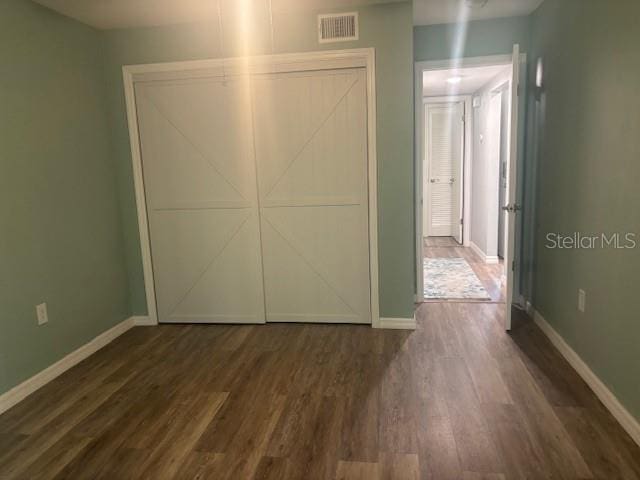 6520 Thicket Trl, New Port Richey, FL 34653 - unfurnished bedroom featuring dark wood-type flooring, baseboards, and a closet