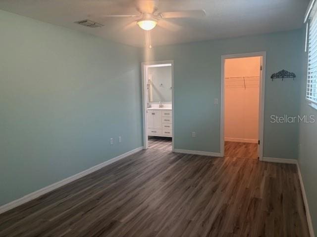 6520 Thicket Trl, New Port Richey, FL 34653 - unfurnished bedroom with a spacious closet, dark wood-style floors, a closet, baseboards, and ensuite bathroom