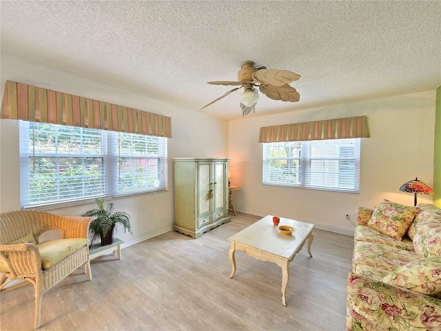 3509 Oak Lake Dr, Palm Harbor, FL 34684 - living area featuring a textured ceiling, a ceiling fan, light wood-style flooring, and baseboards