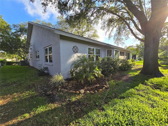 3509 Oak Lake Dr, Palm Harbor, FL 34684 - view of side of property with stucco siding, a lawn, and central AC unit