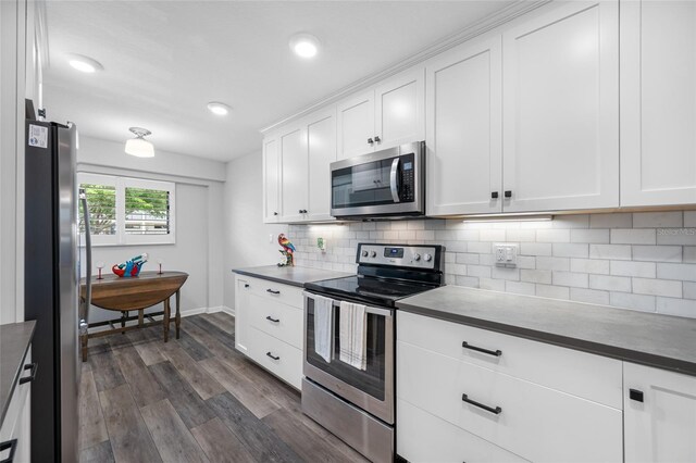 9450 Harbor Greens Way Unit 207, Seminole, FL 33776 - kitchen with stainless steel appliances, dark wood finished floors, decorative backsplash, white cabinets, and recessed lighting