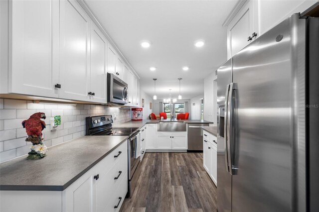 9450 Harbor Greens Way Unit 207, Seminole, FL 33776 - kitchen featuring appliances with stainless steel finishes, a sink, a peninsula, dark wood-style flooring, and white cabinets