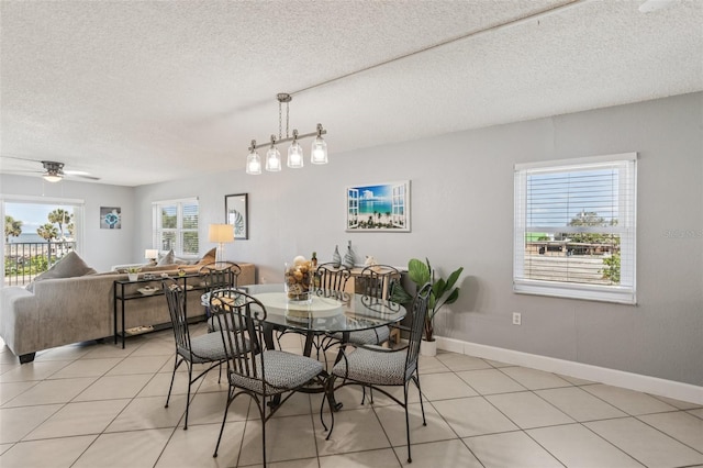 14401 Gulf Blvd Unit 106, Madeira Beach, FL 33708 - dining space with light tile patterned flooring, a textured ceiling, a ceiling fan, and baseboards