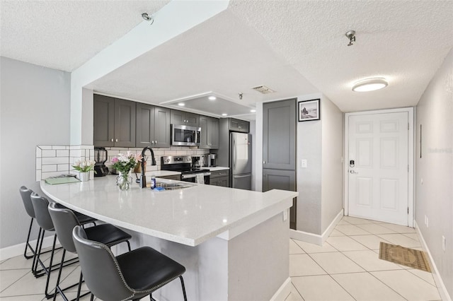 14401 Gulf Blvd Unit 106, Madeira Beach, FL 33708 - kitchen featuring appliances with stainless steel finishes, a textured ceiling, a sink, a peninsula, and baseboards