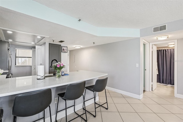 14401 Gulf Blvd Unit 106, Madeira Beach, FL 33708 - kitchen featuring a peninsula, light countertops, a textured ceiling, a kitchen bar, and a sink