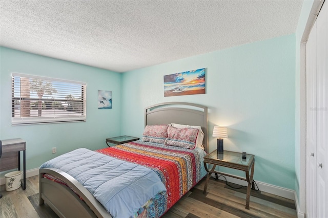 14401 Gulf Blvd Unit 106, Madeira Beach, FL 33708 - bedroom featuring a textured ceiling, wood finished floors, and baseboards