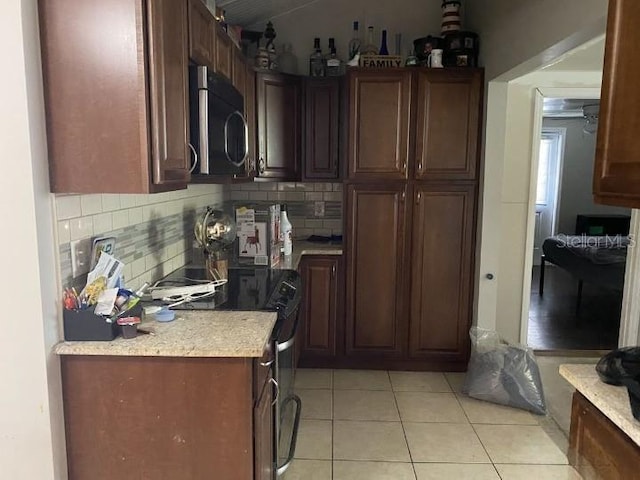 3512 16th St E, Bradenton, FL 34208 - kitchen with stainless steel microwave, electric range, light countertops, light tile patterned flooring, and backsplash