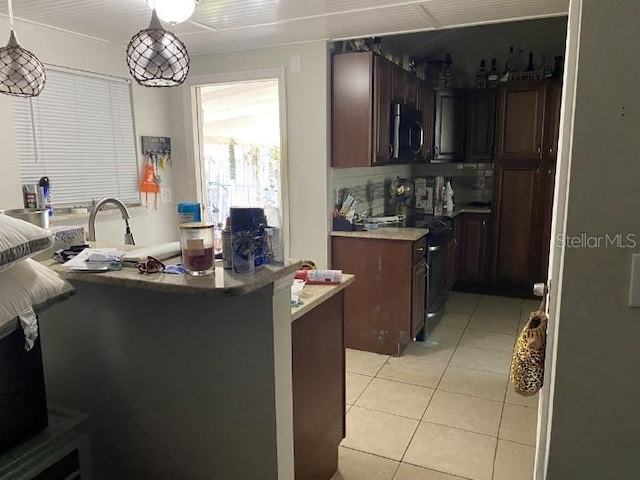 3512 16th St E, Bradenton, FL 34208 - kitchen featuring stainless steel microwave, black range, light tile patterned floors, and dark brown cabinets