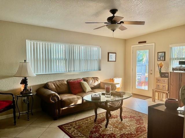 14530 Apache Ave, Largo, FL 33774 - living room featuring light tile patterned floors, a ceiling fan, and a textured ceiling