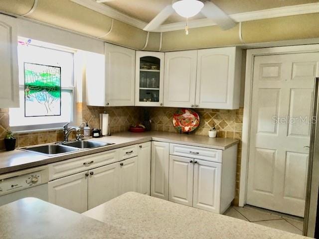 14530 Apache Ave, Largo, FL 33774 - kitchen featuring white cabinetry, a sink, glass insert cabinets, light countertops, and backsplash