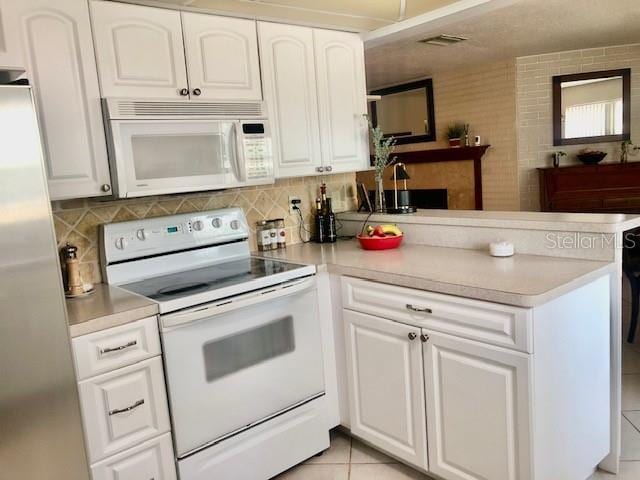 14530 Apache Ave, Largo, FL 33774 - kitchen featuring white appliances, a peninsula, white cabinets, and light countertops