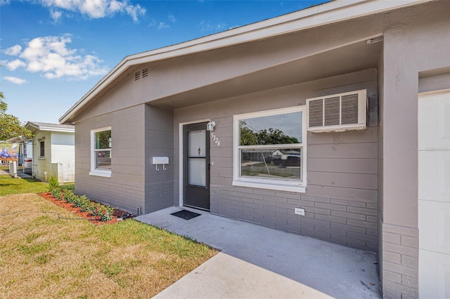 5326 22nd Ave N, Saint Petersburg, FL 33710 - doorway to property featuring a yard, a wall unit AC, and brick siding