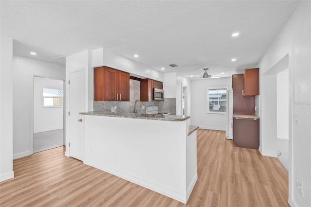 5326 22nd Ave N, Saint Petersburg, FL 33710 - kitchen with stainless steel microwave, stove, light wood-style floors, decorative backsplash, and ceiling fan