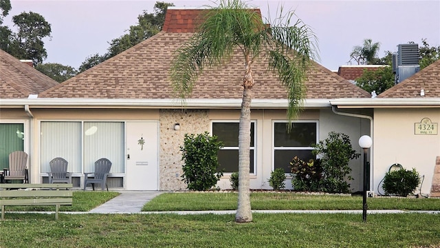 4324 Tahitian Gardens Cir Unit J, Holiday, FL 34691 - rear view of house featuring a shingled roof, a lawn, and stucco siding