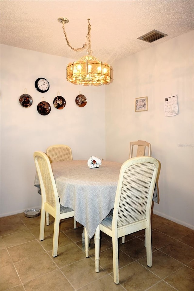 4324 Tahitian Gardens Cir Unit J, Holiday, FL 34691 - tiled dining space featuring a textured ceiling, a chandelier, and baseboards