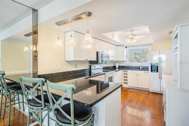 2700 Bayshore Blvd Unit 497, Dunedin, FL 34698 - kitchen with white appliances, a peninsula, a ceiling fan, white cabinets, and a textured ceiling