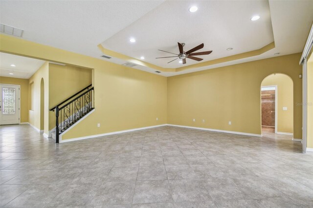 4089 Windcrest Dr, Wesley Chapel, FL 33544 - empty room featuring arched walkways, a tray ceiling, a ceiling fan, recessed lighting, and stairs