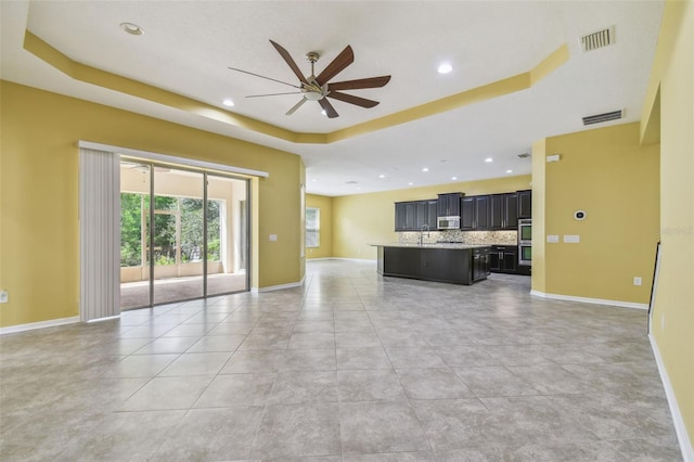 4089 Windcrest Dr, Wesley Chapel, FL 33544 - unfurnished living room featuring a raised ceiling, a ceiling fan, baseboards, recessed lighting, and a sink
