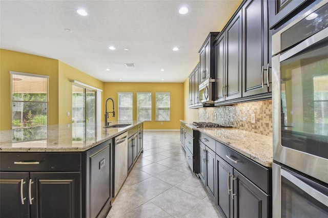 4089 Windcrest Dr, Wesley Chapel, FL 33544 - kitchen with a sink, decorative backsplash, light stone counters, appliances with stainless steel finishes, and recessed lighting