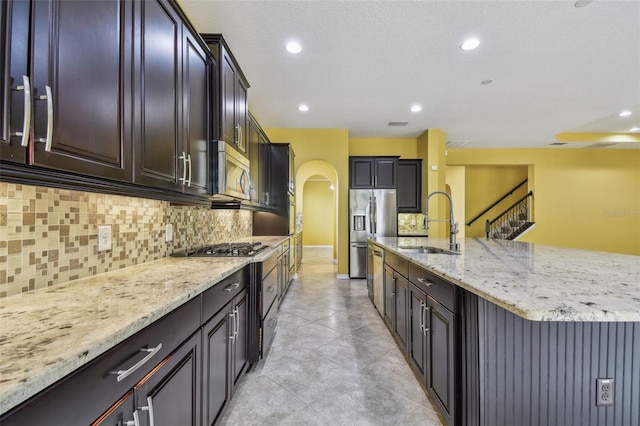 4089 Windcrest Dr, Wesley Chapel, FL 33544 - kitchen with a sink, arched walkways, stainless steel appliances, light stone countertops, and tasteful backsplash