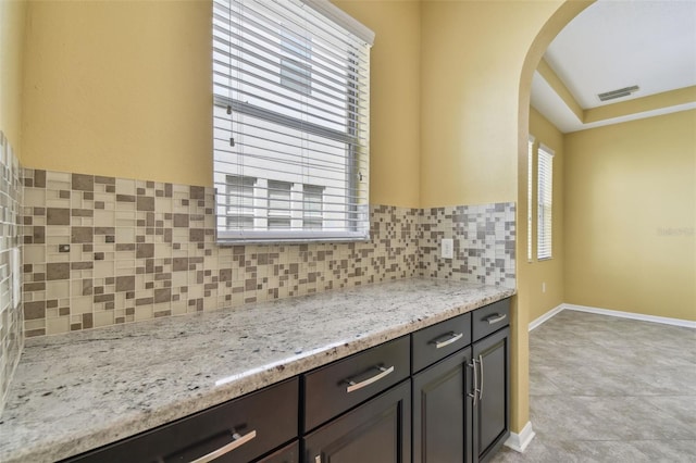 4089 Windcrest Dr, Wesley Chapel, FL 33544 - kitchen with arched walkways, backsplash, light stone countertops, and baseboards