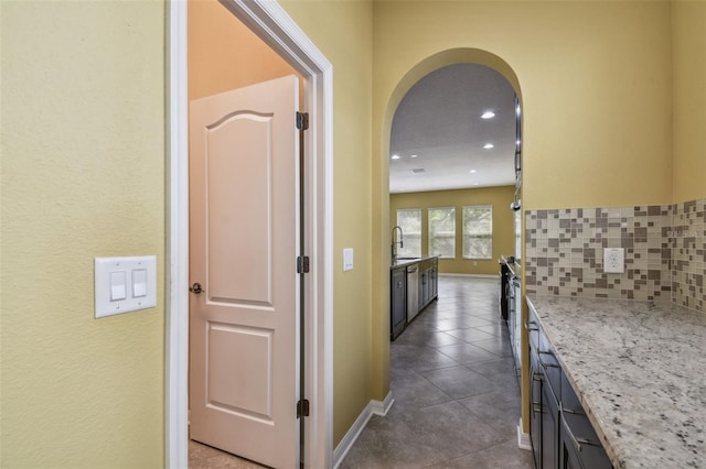 4089 Windcrest Dr, Wesley Chapel, FL 33544 - corridor featuring dark tile patterned flooring, arched walkways, recessed lighting, baseboards, and a sink