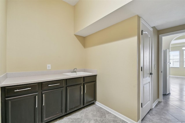 4089 Windcrest Dr, Wesley Chapel, FL 33544 - laundry area with light tile patterned flooring, a sink, baseboards, and arched walkways