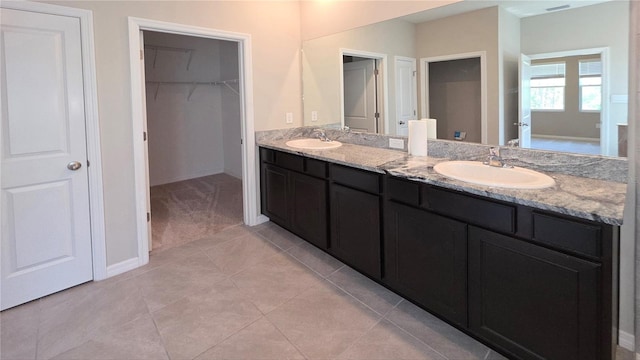 13111 Pepper Stem St, Spring Hill, FL 34609 - full bathroom with double vanity, a walk in closet, baseboards, and tile patterned flooring