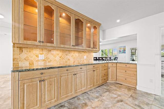 629 Fort Duquesna Dr, Sun City Center, FL 33573 - kitchen with light stone counters, light brown cabinets, backsplash, glass insert cabinets, and recessed lighting