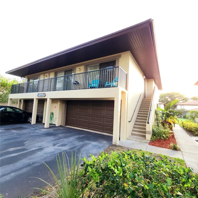 2935 Lichen Ln Unit D, Clearwater, FL 33760 - view of property featuring stucco siding, a garage, stairway, and asphalt driveway